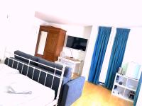 a bedroom with a bed and a tv and blue curtains at VILLA ORCHARD Frankfurt in Zeilsheim