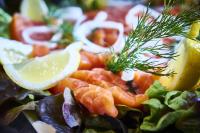 Una ensalada con salmón y limón en un plato. en Logis Bagatelle - 51530 Dizy, en Épernay