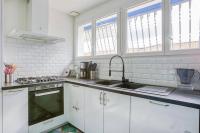 a kitchen with white cabinets and a sink and windows at Maison de vacances Bisca in Biscarrosse