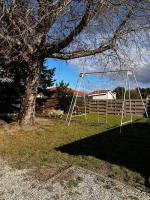 a swing set in a yard next to a tree at Maison de vacances Bisca in Biscarrosse
