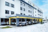an exterior view of a hotel with tables and chairs at B&B HOTEL München-Airport in Hallbergmoos