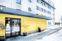 a yellow building with a clock on the side of it at B&B HOTEL München-Airport in Hallbergmoos