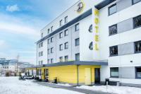 a hotel with a yellow facade in the snow at B&B HOTEL München-Airport in Hallbergmoos