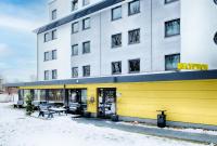 a yellow building with benches in front of it at B&B HOTEL München-Airport in Hallbergmoos