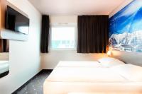 a hotel room with a bed and a tv at B&B HOTEL München-Airport in Hallbergmoos