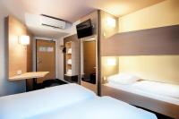 a hotel room with two beds and a desk at B&B HOTEL München-Airport in Hallbergmoos