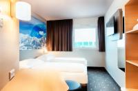 a hotel room with two beds and a tv at B&B HOTEL München-Airport in Hallbergmoos
