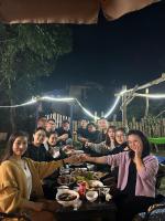 een groep mensen die hand in hand rond een tafel zitten bij Ninh Binh Bamboo Farmstay in Ninh Binh