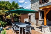 a table and chairs with a green umbrella on a deck at Gîte d&#39;AURE. Classé en meublé 4 étoiles. 