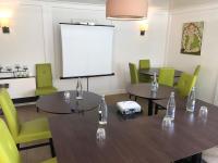 a conference room with tables and chairs and a screen at Hôtel-Restaurant La Mascotte in La Baule