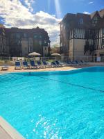 a large swimming pool with blue chairs and buildings at Magnifique appartement 2 pièces in Deauville