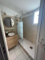 a bathroom with a shower and a sink and a mirror at Superbe appartement 6pers avec piscine et jardin in Fréjus