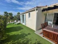 a patio with a table and chairs on a lawn at Superbe appartement 6pers avec piscine et jardin in Fréjus