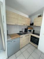 a small kitchen with wooden cabinets and a dishwasher at Superbe appartement 6pers avec piscine et jardin in Fréjus