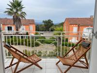 a balcony with two chairs and a view of a house at Superbe appartement 6pers avec piscine et jardin in Fréjus