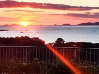 a sunset over the water with a fence and the ocean at Les Rivages de Stagnola Appartement T3 vue mer et montagne plage 200m climatisé in Pietrosella