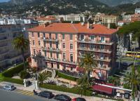 a large pink building with palm trees in a city at Best Western Premier Hotel Prince de Galles in Menton
