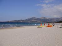 a beach with chairs and umbrellas and the ocean at Appartement F1 Calvi à 150 mètres de la plage in Calvi