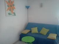 a room with a blue couch with yellow pillows and a table at Appartement F1 Calvi à 150 mètres de la plage in Calvi