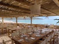 a restaurant with tables and chairs and a view of the beach at Hôtel et Résidence Ta Kladia - Omigna in Cargèse