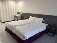 a bedroom with a large bed with white sheets and pillows at Tie Dao Hotel in Tainan