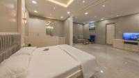 Un dormitorio con una gran cama blanca y un televisor. en The Arowana Divine, en Nanded