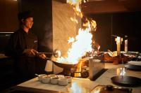 Protur Sa Coma Playa Hotel & Spa في سا كوما: رجل يطهو الطعام في مقلاة ووك مشتعلة