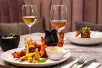 une table avec une assiette de nourriture et deux verres de vin dans l'établissement The Magnolia Hotel, à Quinta do Lago