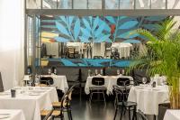 um restaurante com mesas e cadeiras brancas e um mural em Hotel Indigo Belgrade by IHG em Belgrado