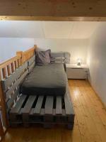 a bed sitting in a room with a wooden bench at Maison de village le BACCI in Vals-les-Bains