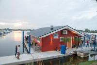 een rood gebouw op een dok naast het water bij Hausboot La Mare Claudia in Weyhe