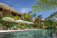 una piscina en un resort con sillas y sombrillas en Villa Lembah Damai by GenuineHost, en Gianyar