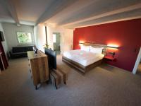 a bedroom with a large bed and a red wall at Sporthotel Igls in Innsbruck