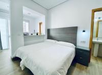 a bedroom with a large white bed and a sink at Apartamentos Turísticos Santo Rostro in Chipiona