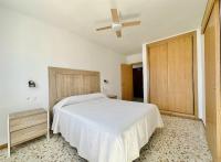 a bedroom with a white bed and a ceiling fan at Apartamentos Turísticos Santo Rostro in Chipiona