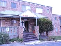 a brick building with a sign that reads reception at Acacia Snowy Motel in Jindabyne