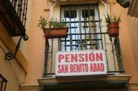 a sign on the side of a building with plants at Pensión San Benito Abad in Seville