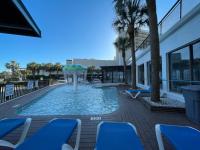 einen Pool mit Sonnenschirm und blauen Stühlen in der Unterkunft Polynesian Oceanfront Hotel in Myrtle Beach
