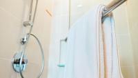 a shower with a white towel hanging on a rack at HARRIS Hotel Batam Center in Batam Center