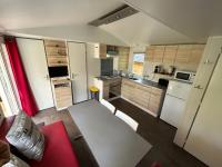 a small kitchen with white appliances and a red couch at LE ILÔ - camping la dune blanche in Camiers