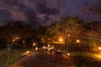 Una mesa de comedor en un jardín por la noche con luces. en Leopard Trails Wilpattu, en Wilpattu