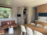 a living room with a dining table and a kitchen at Mobil home PREMIUM 35m2 3 chambres 6 personnes in Arès
