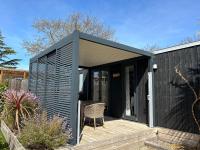 a black shed with a chair on a wooden deck at Mobil home PREMIUM 35m2 3 chambres 6 personnes in Arès