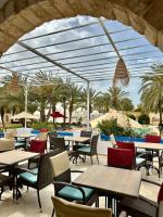 an outdoor patio with tables and chairs and palm trees at Le Patio de Mezraya in Mezraya
