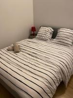 a bedroom with a large bed with striped sheets at Beau F2 Paris face gare de Rosny in Rosny-sous-Bois