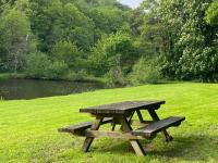 a picnic table and bench in the grass near a pond at Maison Village de La Verrerie in Cherbourg en Cotentin