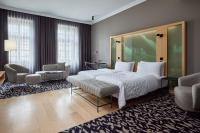 a hotel room with a large bed and chairs at Le Méridien Vienna in Vienna
