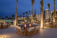 um pátio com mesas, cadeiras e palmeiras em Serry Beach Resort em Hurghada