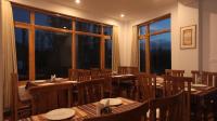 ein Restaurant mit Holztischen und -stühlen und Fenstern in der Unterkunft Hotel Youthok Heritage in Leh