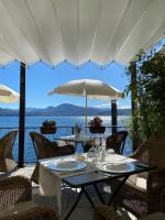 Un patio con mesas y sillas y una sombrilla. en Hotel Cannero, en Cannero Riviera